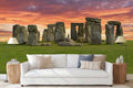 A wall mural featuring the Stonehenge monument at sunset, displayed in a living room setting.